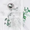 A close-up of a white sheer curtain with a floral pattern and a grommet. A clear plastic rod is visible on the right side. Produktbild-Vorschau
