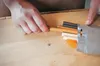 A person's hands are shown holding a wooden stick from a bag of wood repair filler sticks. Anteprima dell’immagine prodotto