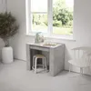 A small desk with a stool and a chair next to a window overlooking a garden. Produktbild-Vorschau