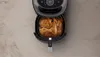 An overhead shot of an air fryer with cooked chicken inside. Produktbild-Vorschau