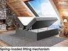 A bed with its storage compartment open, set in a rustic attic room with a fireplace and a large skylight. Produktbild-Vorschau