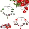 Zwei silberne Charm-Armbänder mit Weihnachtsmotiven und Perlen, eines mit grünen Perlen, eines mit roten Perlen, neben Geschenkboxen und Weihnachtsdekoration Voir les images du produit