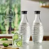 Two glass bottles filled with water and a glass of water with lime and mint are on a table. Produktbild-Vorschau