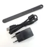A black cleaning brush, USB cable, and power adapter are laid out on a white background. Produktbild-Vorschau