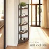 A corner shelf unit with decorative items placed on it, in a room with natural light coming from a large window. Náhled obrázku produktu
