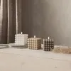 Three bubble cube candles in different colors are arranged on a wooden surface, with a textured curtain in the background. Podgląd zdjęcia produktu