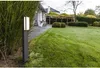A modern outdoor lamp illuminates a well-maintained garden path next to a house. Anteprima dell’immagine prodotto