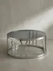 Silberner Couchtisch mit einer runden Platte aus schwarz getöntem Glas und einem geometrischen Edelstahlgestell freigestellt vor weißem Hintergrund._#sku_SAFWL6.674# Produktbild-Vorschau