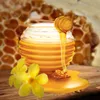 A jar of honey with a honey dipper, two yellow flowers, and a honeycomb background. Podgląd zdjęcia produktu