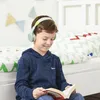 A young boy wearing headphones is reading a book while sitting on the floor next to a bed. Produktbild-Vorschau
