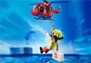 A red rescue helicopter is lifting a Playmobil figure by a rope over a blue ocean. The figure is wearing a yellow helmet and a yellow vest and is holding a white medical bag. Náhľad obrázku produktu