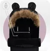 Close-up view of a black stroller footmuff with a fur-lined hood and bear ears, with graphic overlays indicating features. Náhled obrázku produktu