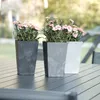 Three planters with pink flowers on a table. Produktbild-Vorschau
