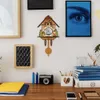 A cuckoo clock is displayed on a wall above a desk with various items. Náhľad obrázku produktu