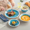A person is eating a meal from a blue and white patterned plate, with other dishes and a glass of water on a table. Produktbild-Vorschau