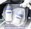 Two baby bottles with blue caps and a stuffed lamb are placed inside a black bag. Podgląd zdjęcia produktu