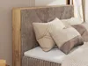 A close-up view of a bed with a textured headboard and decorative pillows. Produktbild-Vorschau