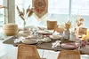A dining table set for a meal with plates, cutlery, glasses, and decorative elements. Produktbild-Vorschau
