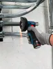 A person's hand wearing a glove is using a cordless angle grinder to cut a metal pipe. Sparks are flying from the cutting action. Voir les images du produit