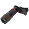 A close-up studio shot of a black and red zoom telephoto lens with a clip attachment, isolated on a white background. Náhled obrázku produktu