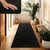 A hallway with a black rug, plants, and wooden furniture. Produktbild-Vorschau