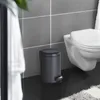 A bathroom scene with a toilet and a trash can. Anteprima dell’immagine prodotto