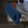 A dark blue smartphone case is shown falling towards a white sneaker. Anteprima dell’immagine prodotto