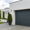 A modern house with a garage door and a potted plant in front. Produktbild-Vorschau