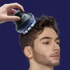 Schwarzer und klar blauer Kopfhautmassager, von einer Hand gehalten, verwendet auf dem Kopf eines Mannes Voir les images du produit