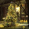 A Christmas tree decorated with lights in the snow outside a house. Anteprima dell’immagine prodotto