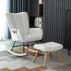 A white rocking chair and ottoman are placed on a patterned rug in a room with bookshelves in the background. Podgląd zdjęcia produktu