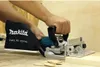 A person is using a Makita biscuit joiner on a wooden surface. Podgląd zdjęcia produktu