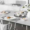 A dining table set for a meal with plates, glasses, and food. Produktbild-Vorschau