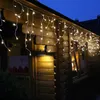 Icicle lights are strung along the eaves of a wooden house at dusk. Produktbild-Vorschau