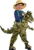 Kind im T-Rex Kostüm „Reitender Dino“ mit Hosenträgern, braun-grünem Schuppendesign und realistischem Dino-Kopf. Produktbild-Vorschau
