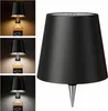 A collage of a black table lamp with a conical shade, mounted on a bottle. The lamp is shown in different lighting conditions. Voir les images du produit