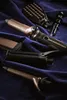 A collection of hair styling tools laid out on a dark purple velvet fabric. Produktbild-Vorschau