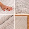 A collage of four images showing different close-up views of a beige rug with a geometric pattern. One image shows a hand touching the rug, another shows the texture of the rug, a third shows the rug rolled up, and the fourth shows a corner of the rug on a Podgląd zdjęcia produktu