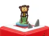 A close-up shot of a Tonies Hörfigur toy on a red base, with a monkey figure sitting on a green island surrounded by blue water, and two grey shark fins protruding from the surface. Produktbild-Vorschau