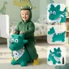 A young child in a green dinosaur costume is happily riding a green inflatable dinosaur toy in a bedroom. Podgląd zdjęcia produktu