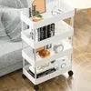 A white four-tier rolling cart filled with various decorative items and books, placed next to a gray sofa on a wooden floor. Podgląd zdjęcia produktu
