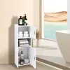 A white bathroom cabinet with two doors, one open, displaying toiletries and folded towels. The cabinet is placed in a bright, modern bathroom setting with a large window showing a desert landscape and a bathtub. Produktbild-Vorschau