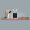 A black UbiQuiti Networks airCube router is placed on a wooden shelf next to a cup of pencils and a small red figurine. A Wi-Fi symbol is shown above the router. Produktbild-Vorschau