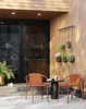 A patio scene with two chairs, a small table, and hanging plants. Produktbild-Vorschau