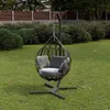 A hanging chair with cushions is placed on a grassy lawn in a garden setting, with bushes and a fence in the background. Náhled obrázku produktu