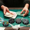 A person is crafting a card with various small items like buttons, paper clips, and decorative elements. Produktbild-Vorschau