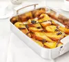 A close-up view of a roasting pan filled with baked pears, cinnamon sticks, star anise, and vanilla beans. Produktbild-Vorschau