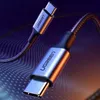 A close-up shot of two USB-C cables with metallic connectors and braided cables, set against a dark, abstract background with glowing lines. Produktbild-Vorschau