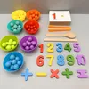 A collection of Montessori learning materials for children, including colored bowls filled with small balls, number cards, and counting tools, arranged on a gray surface. Produktbild-Vorschau