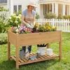 A woman is gardening in a raised planter in a backyard setting. Produktbild-Vorschau